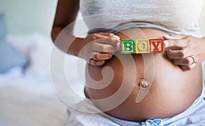 Precious baby boy on board. a pregnant woman with wooden blocks on her belly that spell the word boy.