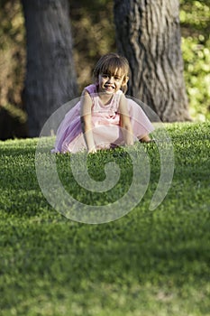 Precious ittle girl in pink dress on grass