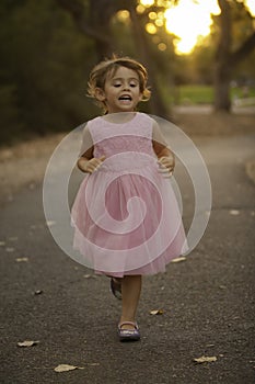 Precious ittle girl in pink dress running at dusk