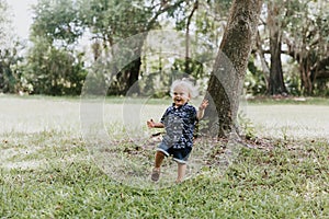 Precious Little Toddler Boy Dressed Up in the Outdoors Forest Park for Portraits in Autumn by Big Natural Tree Having Excited Fun