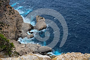 On a precipice. View from the cliff on the waves breaking on the shore. Cape Formentor. Majorca. Spain