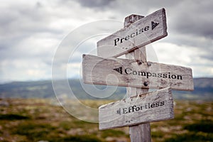 precise compassion effortless text engraved on old wooden signpost outdoors in nature photo