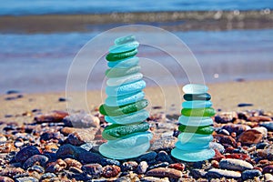 Precisely balanced pyramids of glass stones from broken bottles polished by the sea against the backdrop of the sea