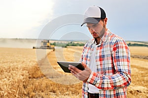 Precision farming. Farmer holding tablet for combine harvester guidance and control with modern automation system