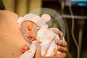 Preemie baby girl enjoying skin to skin with dad photo