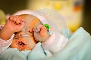 Preemie baby girl rubbing her eyes in the nicu