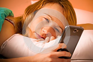 Preety woman reading a sms on cell phone in bed