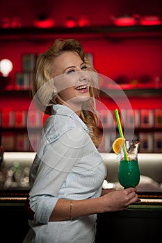 Preety young woman drinks cocktail in a night club