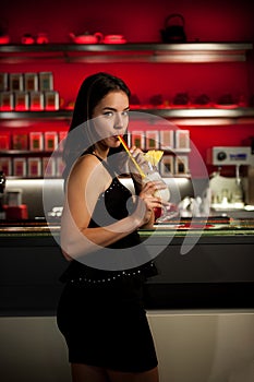 Preety young woman drinks cocktail in a night club