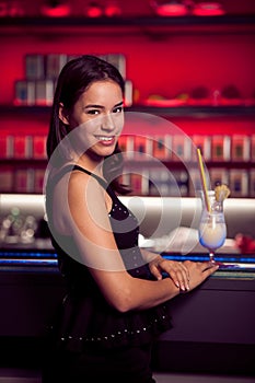 Preety young woman drinks cocktail in a night club