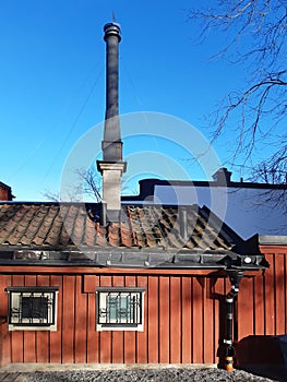 Prefab building roof with industrial black chimney under blue sky. Architecture and construction detail