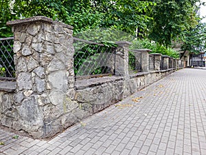 Prefab metal fence on concrete foundation pile of stones loose stone construction of houses and yards construction works