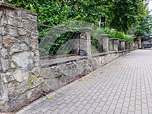 Prefab metal fence on concrete foundation pile of stones loose stone construction of houses and yards construction works