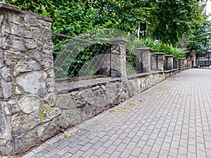 prefab metal fence on concrete foundation pile of stones loose stone construction of houses and yards construction works