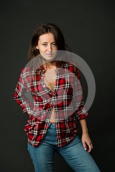 She prefers casual style. Country style. Woman checkered shirt. Attractive confident girl black background. Sexy people