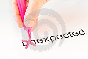 The prefix `un` of the word unexpected is crossed out with a pink pencil by a hand