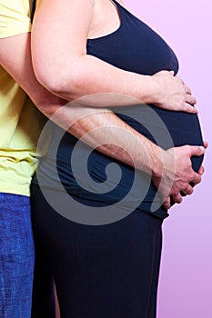 Pregant woman with husband both holding the baby