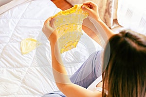 Pregnancy baby clothes. Beautiful pregnant mother with yellow baby clothes. Pregnancy woman hugging belly and packing