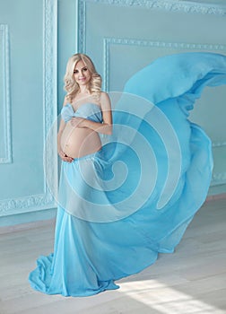 Pregnancy, Beautiful pregnant woman. Happy motherhood. Attractive blonde touching naked belly posing in blowing drapery dress fly