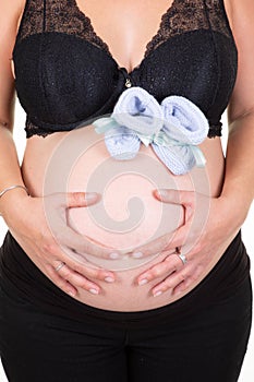 Pregnancy belly tummy of pregnant woman with baby first shoes on white background