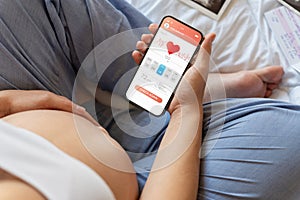 Pregnancy calendar app. Mobile pregnancy online maternity application. Pregnant mother using phone. Concept of pregnancy
