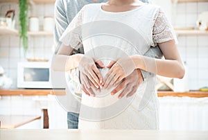 Pregnancy concept - couple making heart shape with their hands on pregnant belly,.Pregnant Woman and Husband holding hands in