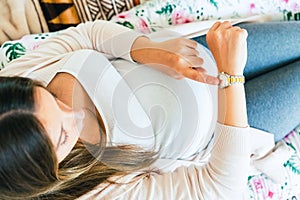 Pregnancy contractions time. Childbirth time, contractions pain. Pregnant holding baby belly, woman watching clock