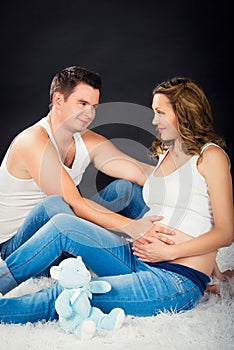 Pregnancy couple lying hugging on a black background