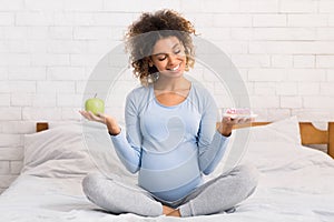 Pregnancy and food choice. Expectant woman with apple and donut