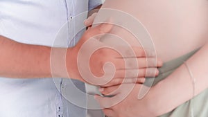 pregnancy, happy spouses are expecting the birth of a baby and stroking their belly with their hands at home, close-up