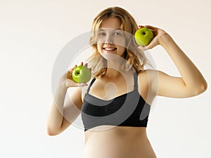 Pregnancy, healthy food and people concept close up of happy pregnant woman eating green apple at studio