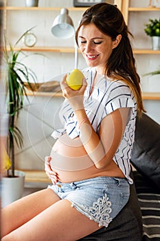 Pregnancy, healthy food and people concept Happy pregnant woman eating apple. healthy food.