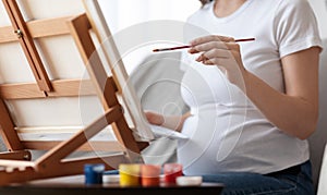 Pregnancy And Leisure. Unrecognizable Pregnant Woman Painting On Easel At Home, Closeup