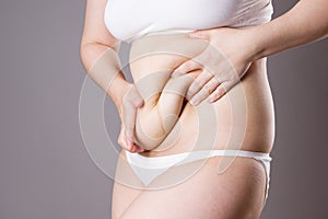 Pregnancy line - linea nigra, tummy tuck, overweight female body and flabby belly on gray background