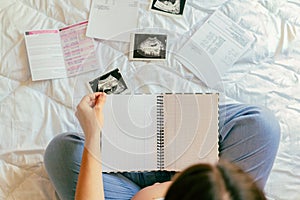 Pregnancy list woman writing. Beautiful pregnant woman writing check list. Happy pregnancy lady holding notepad. Concept
