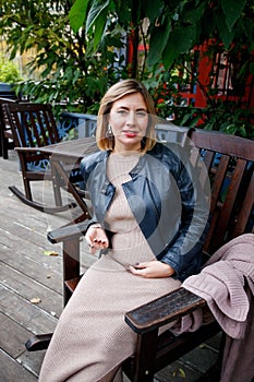 Pregnancy, maternity and happiness. Stylish young pregnant female having rest in park, sitting on wooden armcheir. Beautiful woman