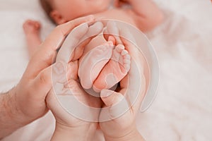 Pregnancy, maternity, preparation and expectation motherhood, giving birth concept. Newborn baby feet in hands of parents