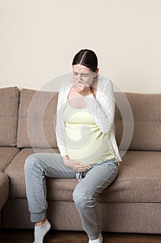 Pregnancy Morning Sickness. Pregnant Woman Having Nausea Feeling Bad in Sofa at the Home