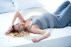 Pregnancy and motherhood. Beautiful pregnant lying on the bed in the shine of sunlight