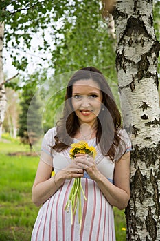 Pregnancy, motherhood, the concept of waiting-close - up of a happy pregnant woman with a big belly with a bouquet of flowers at t