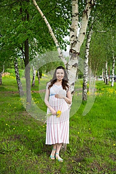 Pregnancy, motherhood, the concept of waiting-close - up of a happy pregnant woman with a big belly with a bouquet of flowers at t