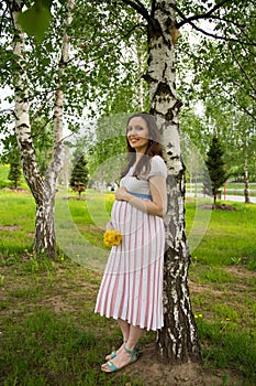 Pregnancy, motherhood, the concept of waiting-close - up of a happy pregnant woman with a big belly with a bouquet of flowers at t