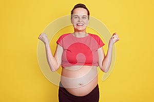 Pregnancy, motherhood, expectation baby. Close up portrait of happy pregnant woman with big bare belly standing with excitement