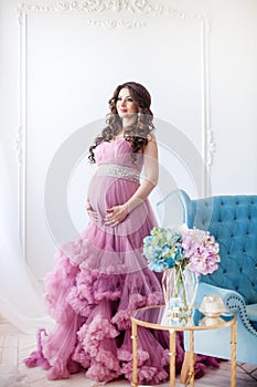 Pregnancy, motherhood and expectation concept - a pregnant woman dressed in a beautiful pink dress