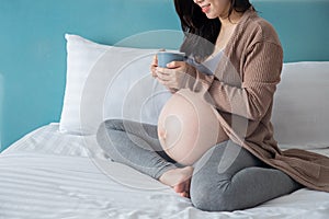 Pregnancy, motherhood and expectation concept - smiling pregnant woman drink some milk