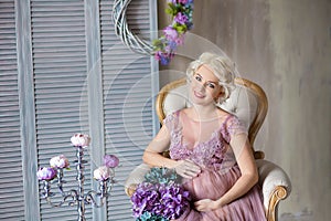 Pregnancy, motherhood and happy future mother concept - pregnant woman in airy violet dress with bouquet flowers against colorful