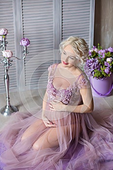 Pregnancy, motherhood and happy future mother concept - pregnant woman in airy violet dress with bouquet flowers against colorful