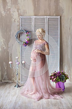 Pregnancy, motherhood and happy future mother concept - pregnant woman in airy violet dress with bouquet flowers against colorful