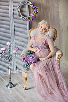 Pregnancy, motherhood and happy future mother concept - pregnant woman in airy violet dress with bouquet flowers against colorful