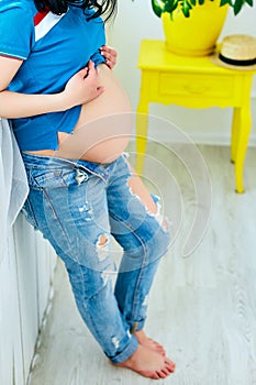 Pregnancy, motherhood and happy future mother concept. Pregnant woman holding her belly studio